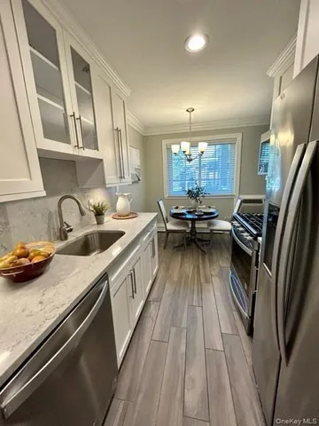 a kitchen with counter top space a sink wooden floor and stainless steel appliances