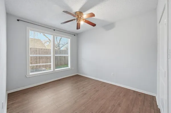 an empty room with wooden floor fan and windows