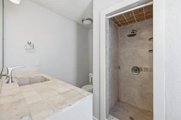 a bathroom with a tub shower vanity and a sink