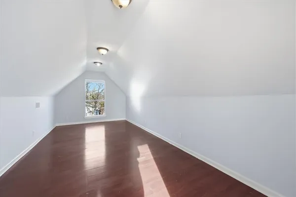 a view of an empty room with wooden floor and window