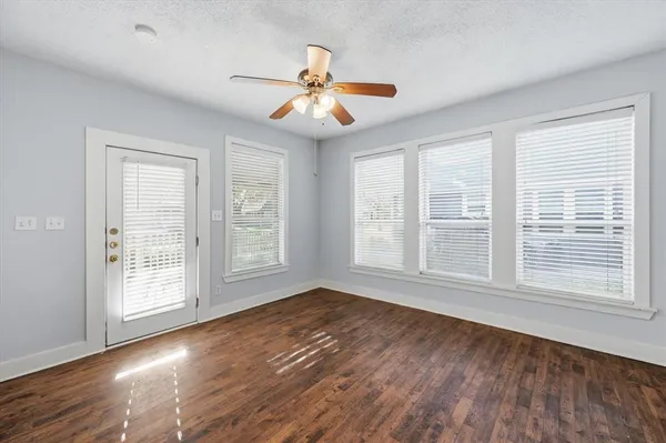 a view of an empty room with wooden floor and a window