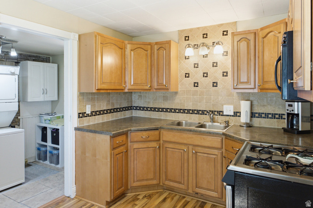 94 West 2000th Street North Clearfield, UT 84015 - Photo 10 of 26 Kitchen featuring wood cabinetry, tile backsplash, gas range, and convenient access to the laundry/utility area.