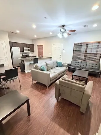 a living room with furniture pool table and wooden floor
