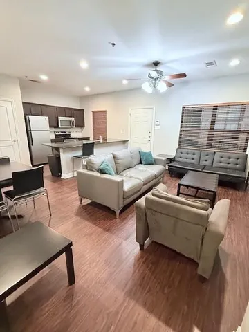 a living room with furniture pool table and wooden floor