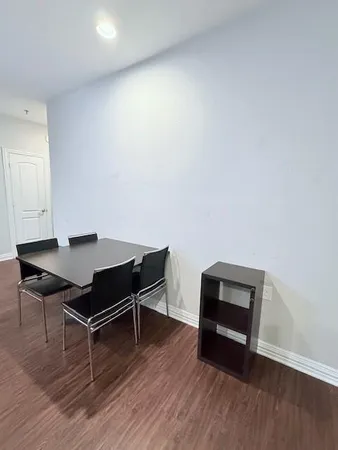 a living room with stainless steel appliances wooden floors and a view of kitchen