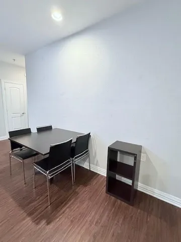 a living room with stainless steel appliances wooden floors and a view of kitchen