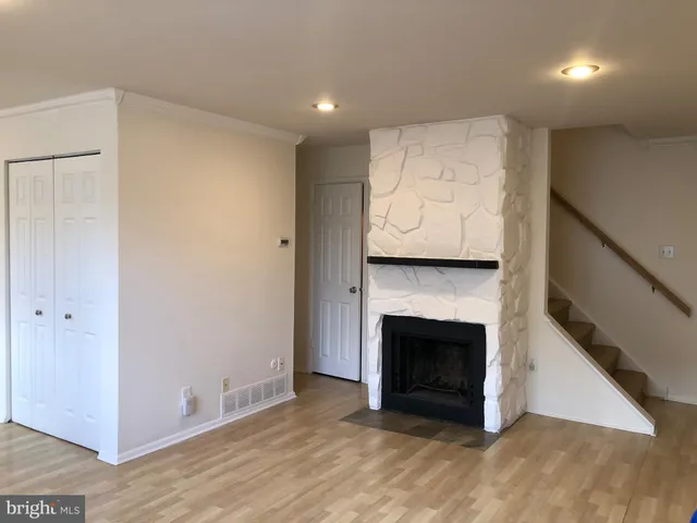 a view of an empty room with wooden floor and a fireplace