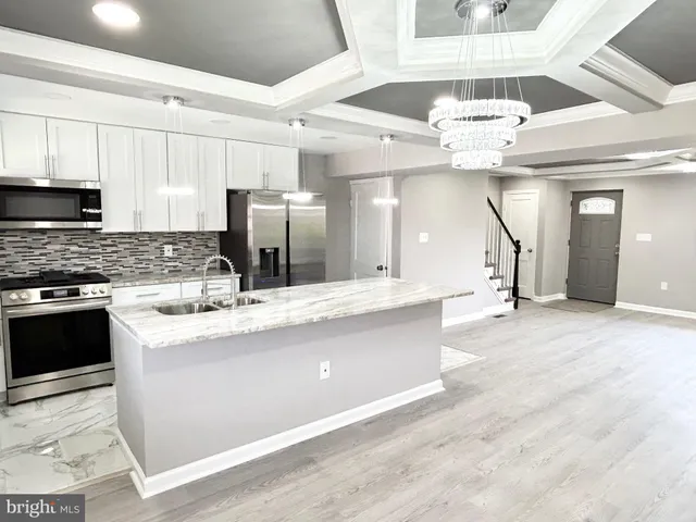 a large kitchen with stainless steel appliances a large counter top a stove and cabinets