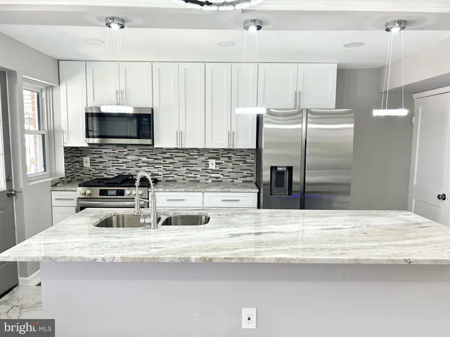 a kitchen with kitchen island a sink stainless steel appliances and cabinets