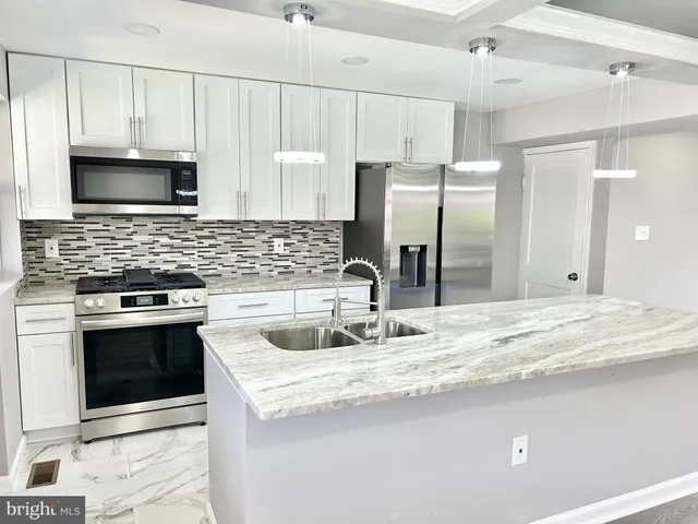 a kitchen with stainless steel appliances granite countertop a sink a stove and a refrigerator