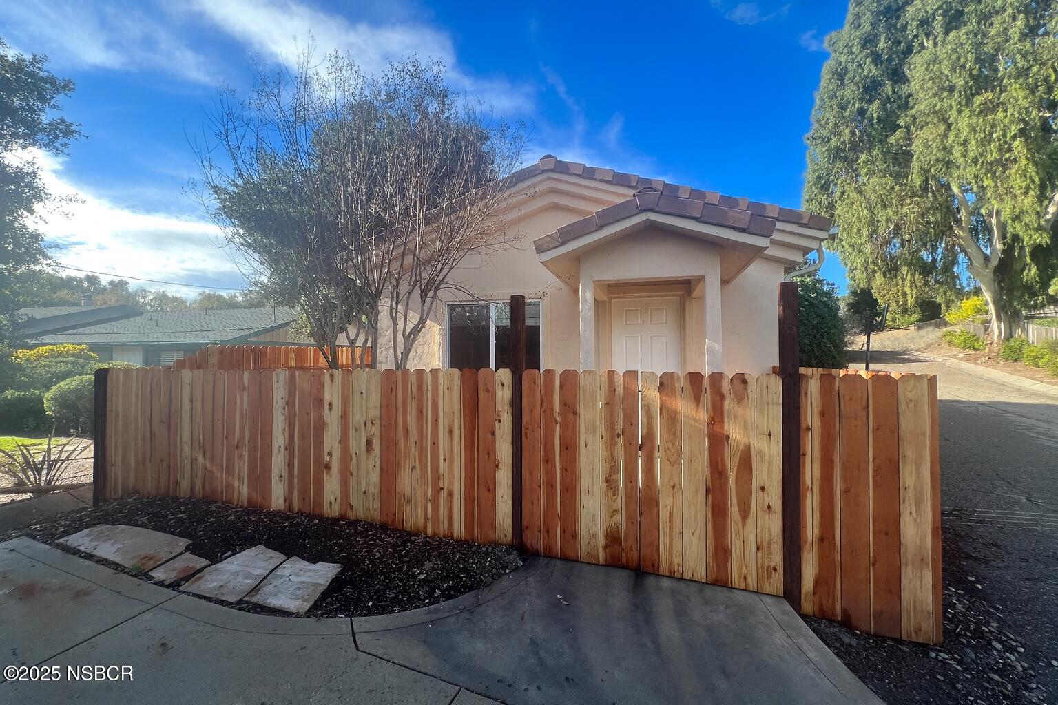 a view of a house with wooden fence next to a yard