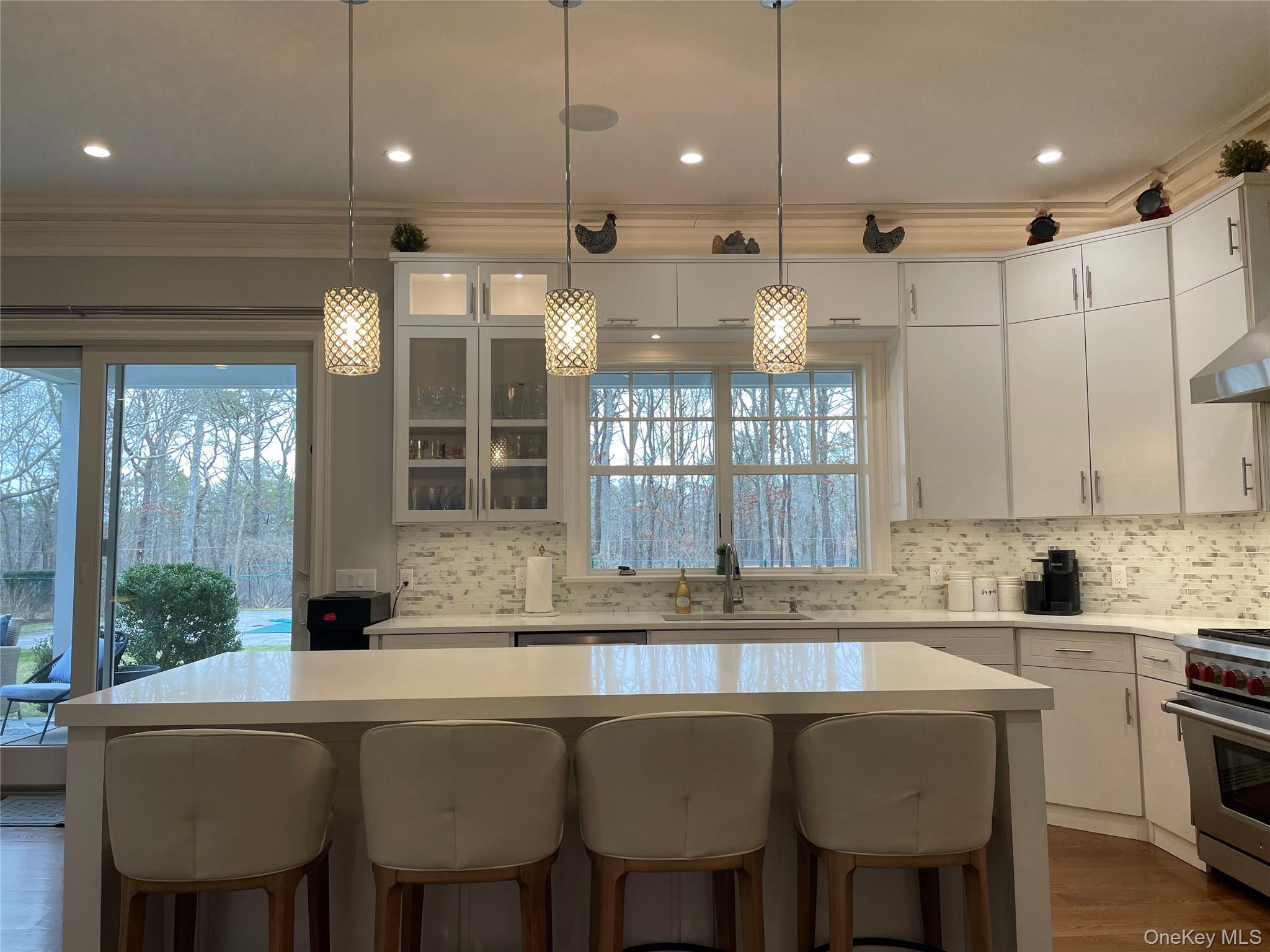 99 Spinney Road East Quogue, NY 11942 - Photo 10 of 40 a kitchen with a dining table chairs and white cabinets