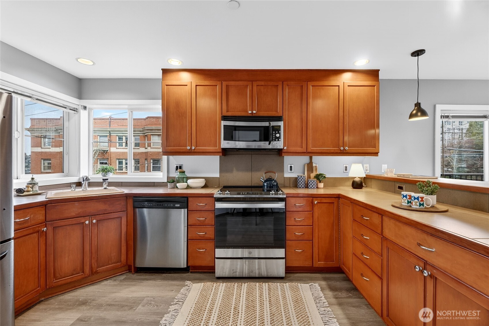 321 East Thomas Street, Unit 303 Seattle, WA 98102 - Photo 5 of 24 a kitchen with stainless steel appliances granite countertop wooden cabinets stove top oven and sink