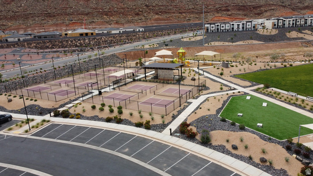 1693 Devils Gdn Lane Washington, UT 84780 - Photo 49 of 64 Community amenity area featuring multiple pickleball courts, a central shaded pavilion, a children's play structure with shade canopies, an artificial turf recreation area, and extensive hardscaping with desert landscaping