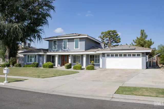 a view of a white house with a big yard and potted plants
