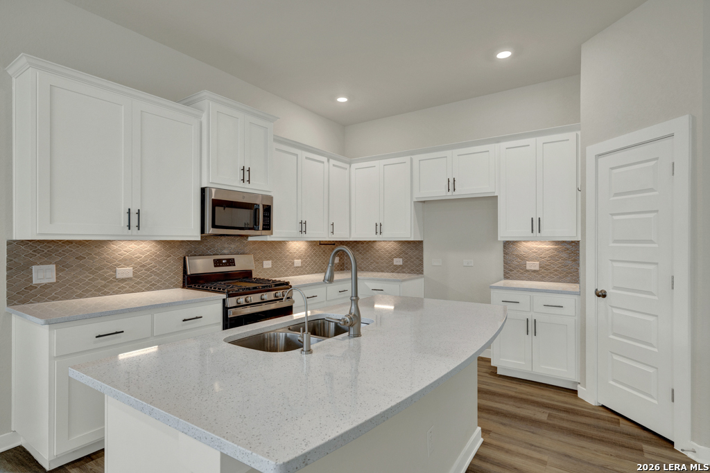 1433 Escarpment Road New Braunfels, TX 78132 - Photo 11 of 37 a kitchen with stainless steel appliances a sink a stove a microwave a center island and cabinets