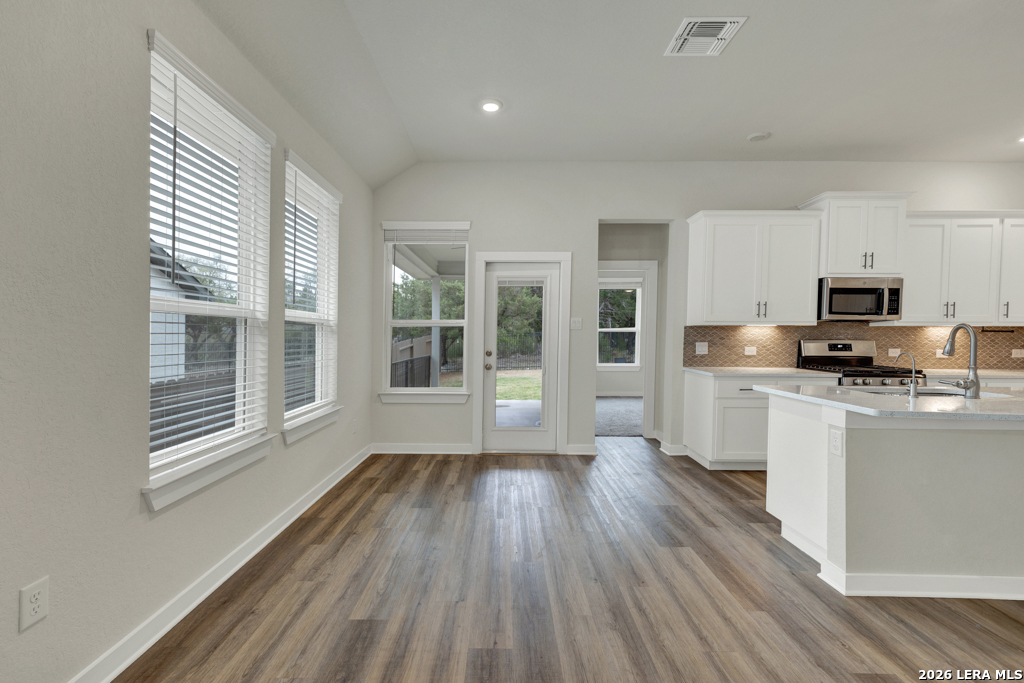 1433 Escarpment Road New Braunfels, TX 78132 - Photo 9 of 37 a kitchen with wooden floors and white cabinets