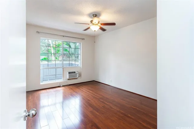an empty room with wooden floor fan and windows