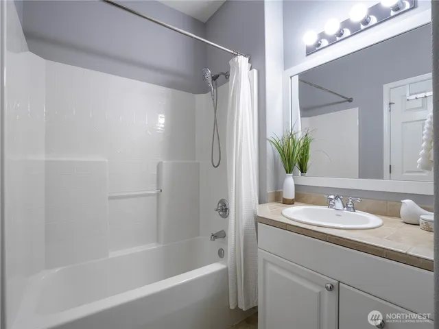 a bathroom with a granite countertop sink a mirror a shower and a bathtub