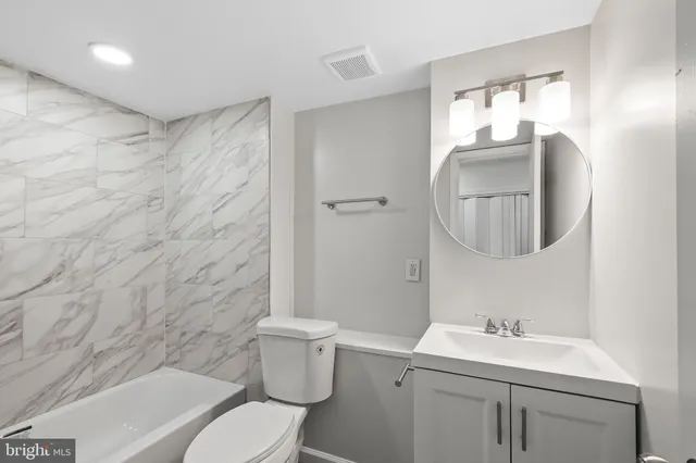 a bathroom with a toilet a sink a mirror a vanity and shower