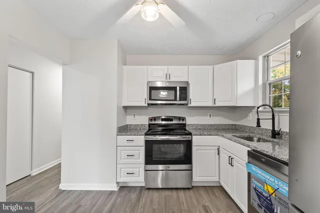 a kitchen with granite countertop white cabinets and stainless steel appliances