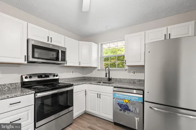 a kitchen with granite countertop a refrigerator stove and microwave