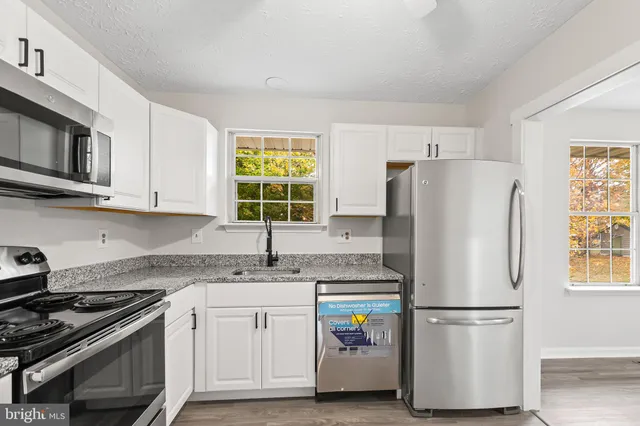 a kitchen with stainless steel appliances granite countertop a refrigerator sink and stove