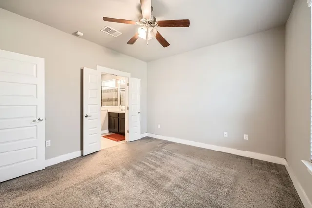 an empty room with chandelier fan and windows