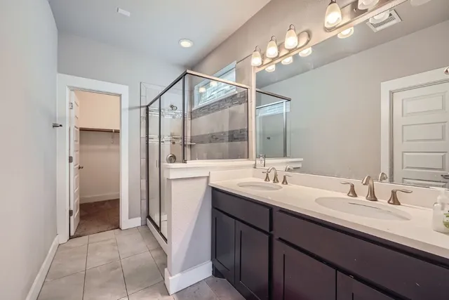 a bathroom with a double vanity sink a mirror and a shower