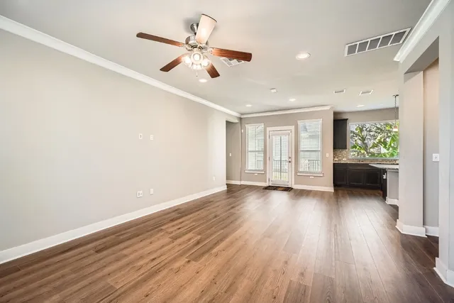 a view of an empty room with a window and wooden floor