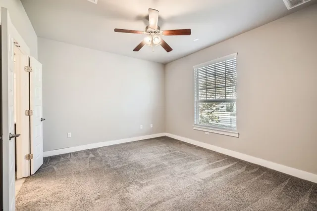 an empty room with windows and fan