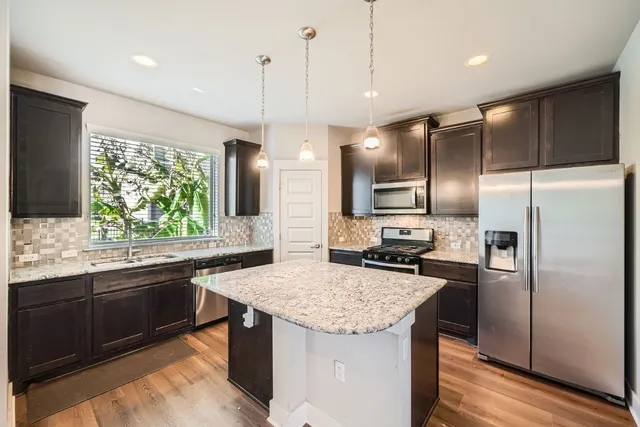a kitchen with granite countertop stainless steel appliances a sink stove and refrigerator