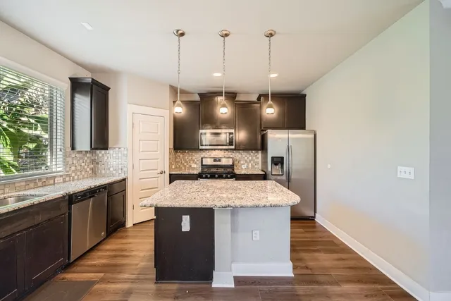 a large kitchen with a center island wooden floor and a large window