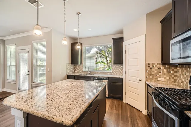 a kitchen with kitchen island granite countertop wooden cabinets and a stove