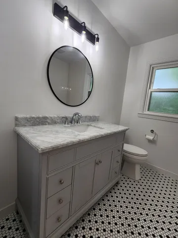 a bathroom with a granite countertop toilet a sink and a mirror