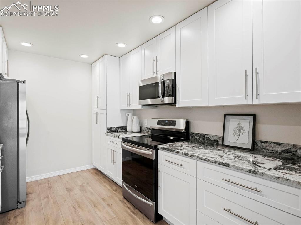2622 Spring Grove Terrace Colorado Springs, CO 80906 - Photo 6 of 37 a kitchen with stainless steel appliances granite countertop a stove a refrigerator and a microwave