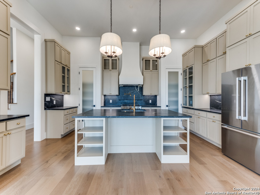 a large kitchen with a center island wooden floor stainless steel appliances and cabinets