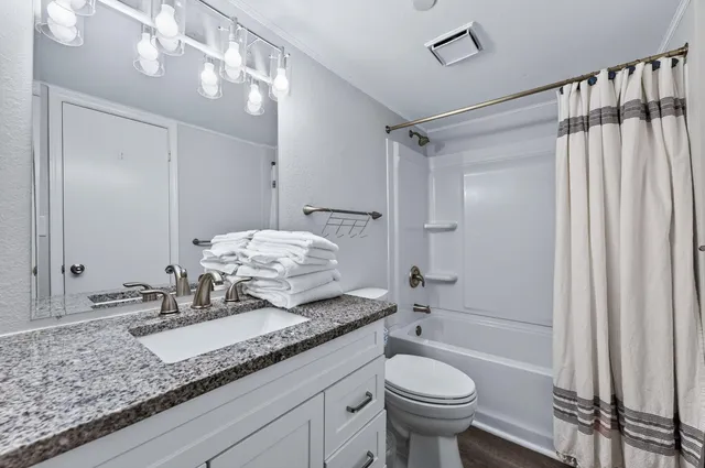 a bathroom with a granite countertop sink toilet and shower