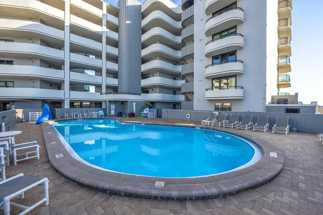a view of a swimming pool with a chairs in front of house