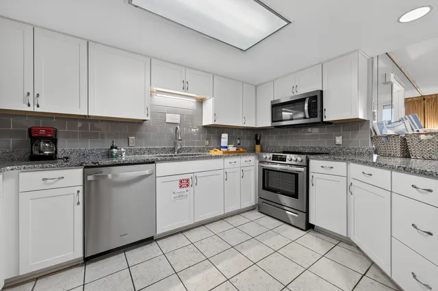 a kitchen with white cabinets appliances and a sink