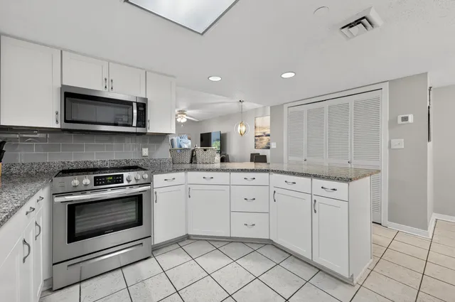 a kitchen with granite countertop white cabinets stainless steel appliances and a sink