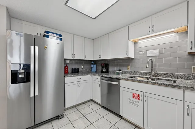 a kitchen with stainless steel appliances granite countertop a refrigerator sink and white cabinets