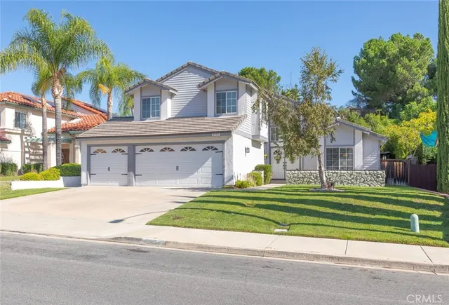 a front view of a house with a garden and trees