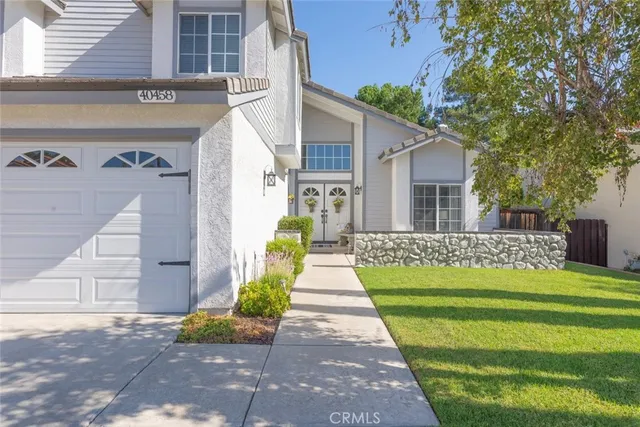 a front view of a house with a garden and trees