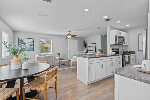 a kitchen with granite countertop a table chairs stove and white cabinets