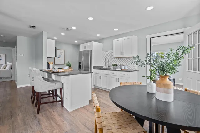 a kitchen with a table chairs and white cabinets