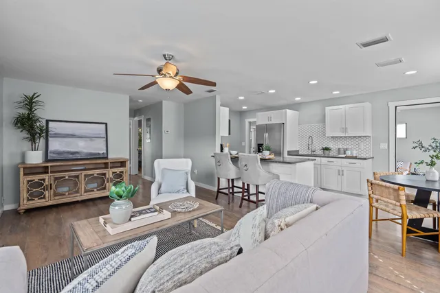 a living room with furniture a flat screen tv and kitchen view