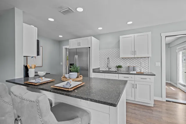 a kitchen with kitchen island granite countertop a sink cabinets and wooden floor