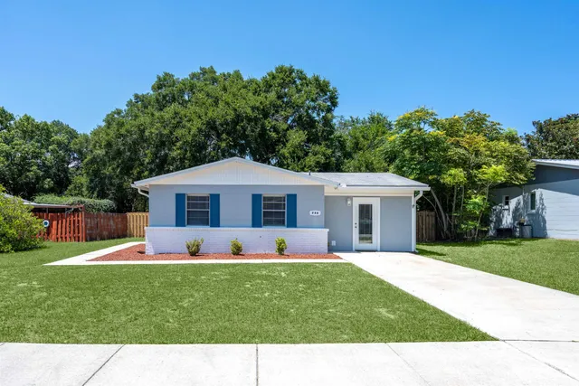 a view front of house with a yard potted plants and large tree