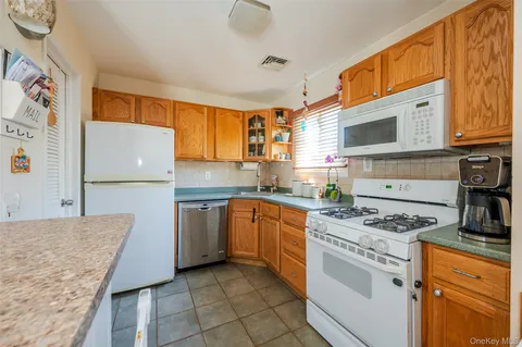 a kitchen with stainless steel appliances granite countertop a stove top oven a refrigerator a sink and dishwasher with white cabinets